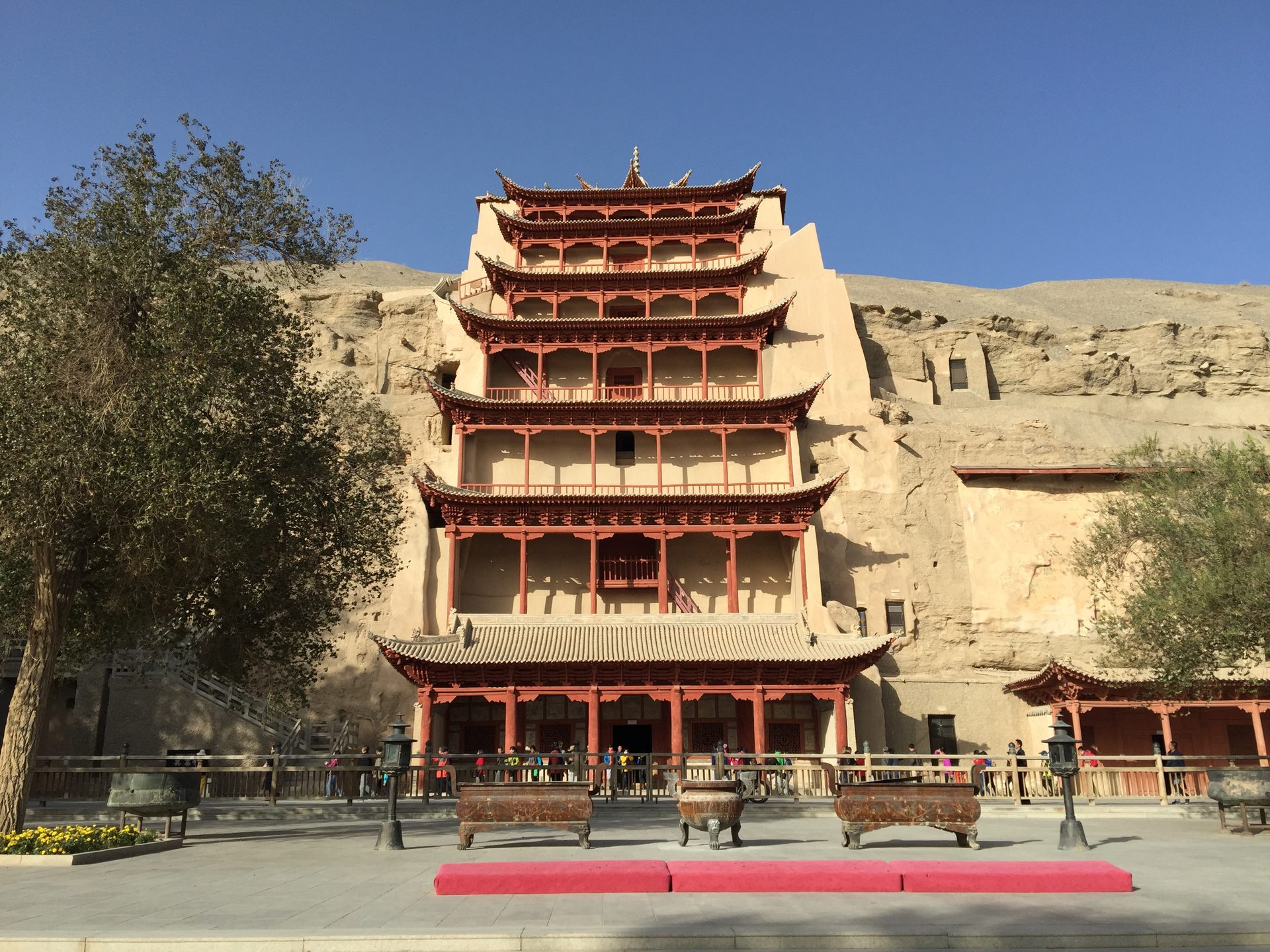 The nine-storey red timber facade of Cave 96 at Mogao Caves built into the desert cliff, Dunhuang — Photo: 慕尼黑啤酒 / CC BY-SA 3.0 via Wikimedia Commons
