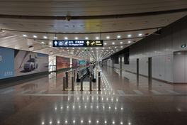 Arrival corridor at Beijing Capital Airport Terminal 2 with overhead signs for Exit, Baggage Claim and Transfer — Photo: 颐园居 / CC BY-SA 4.0 via Wikimedia Commons