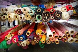 Colorful rolls of fabric stacked on racks at a textile market stall